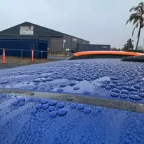 Water beading on a freshly coated blue car